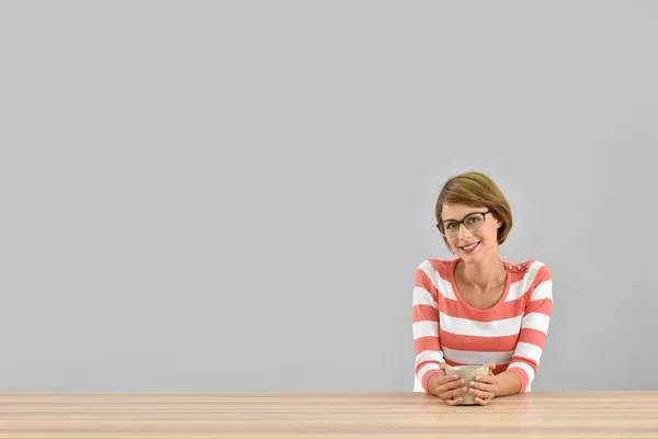 Femme assise à table avec tasse — Photo