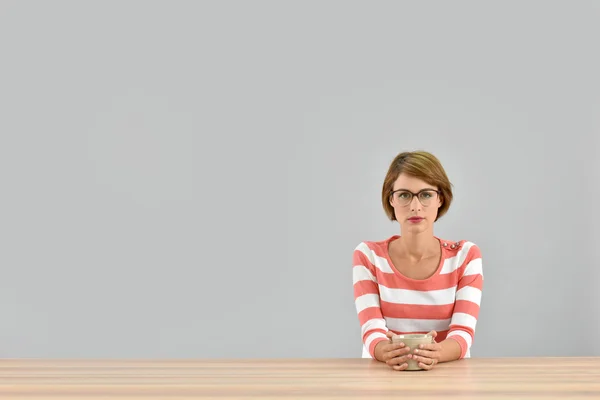 Femme assise à table avec une tasse de thé — Photo