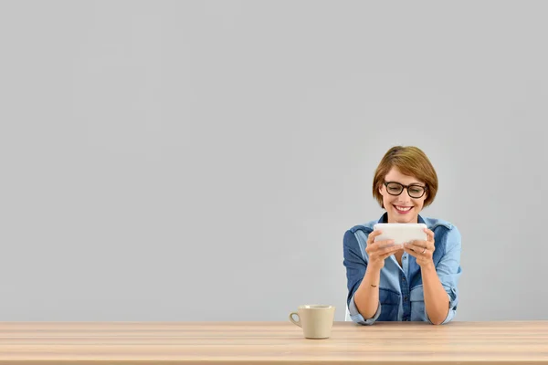 Woman sitting at desk using smartphone Royalty Free Stock Photos