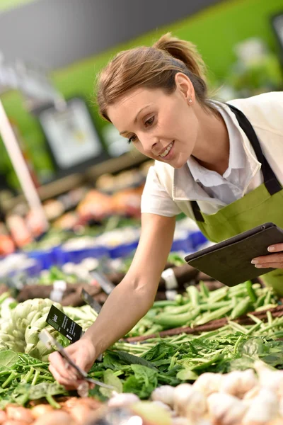 Pracownika supermarketu stawianie warzywa — Zdjęcie stockowe