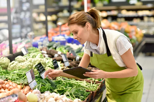 Supermercado empregado colocando legumes — Fotografia de Stock