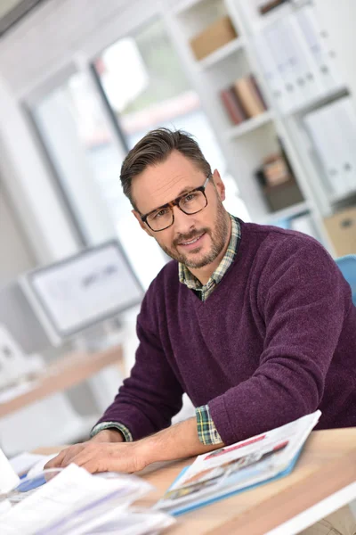 Empresário sorridente com óculos sentados — Fotografia de Stock