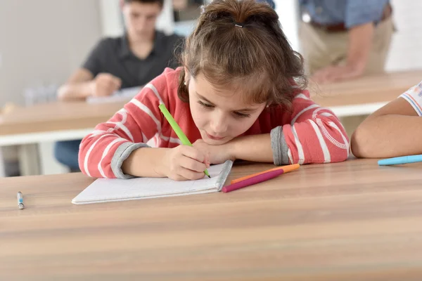 Scolaretta in classe che scrive su taccuino — Foto Stock