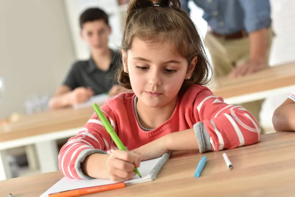 Écolière mignonne en classe écriture — Photo