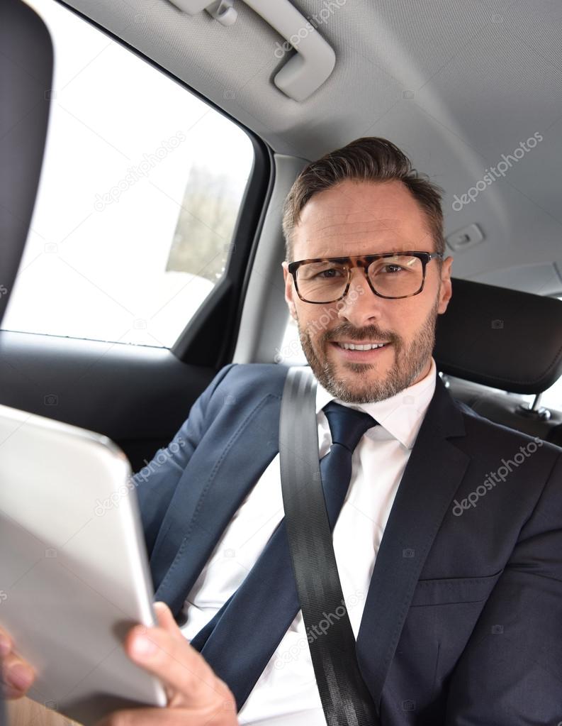 Businessman in taxi cab reading news