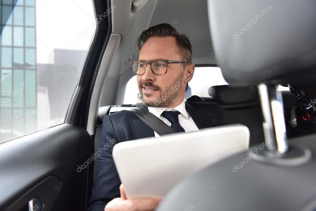 Businessman in taxi cab reading