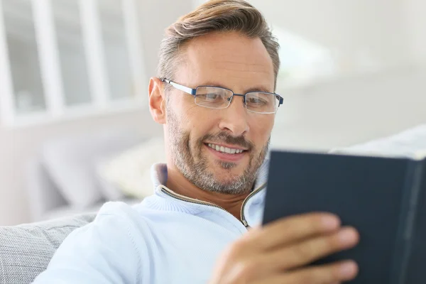 Koppla av i soffan läser bok — Stockfoto