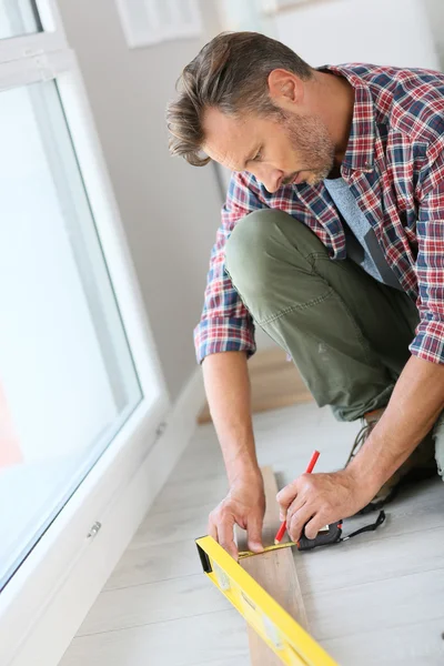 Homme à la maison mesurant la planche de bois — Photo