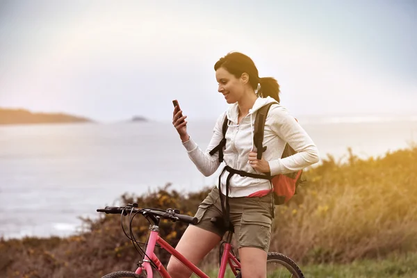 Woman on biking journey reading message — Stock Photo, Image