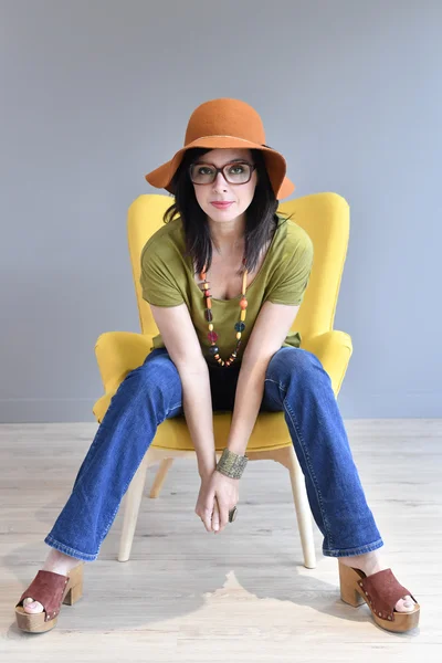 Модна жінка з капелюхом на сидячому — стокове фото