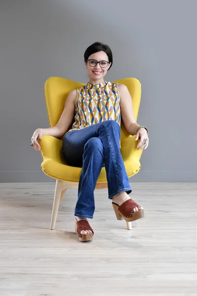 Femme relaxante dans un fauteuil jaune — Photo