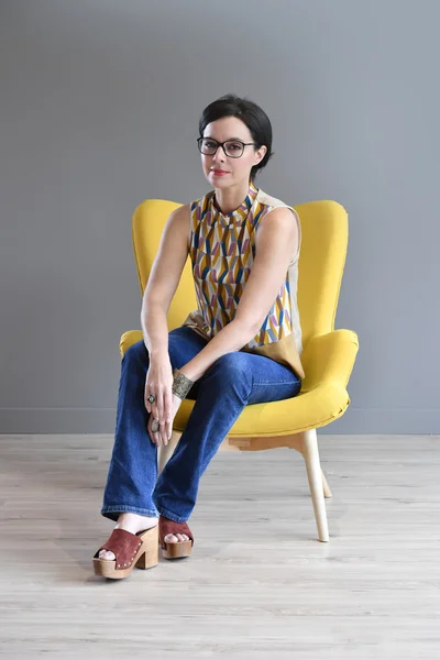 Woman relaxing in yellow armchair — Stock Photo, Image