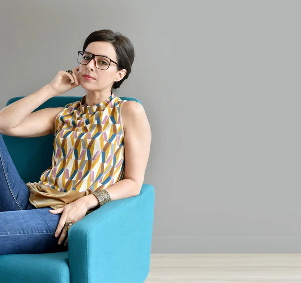 Trendy girl sitting in blue armchair — Stock Photo, Image