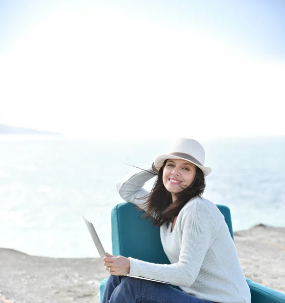 Mulher com chapéu sentado junto ao mar — Fotografia de Stock
