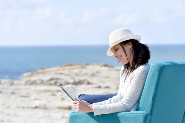 Frau liest Buch im Sessel — Stockfoto