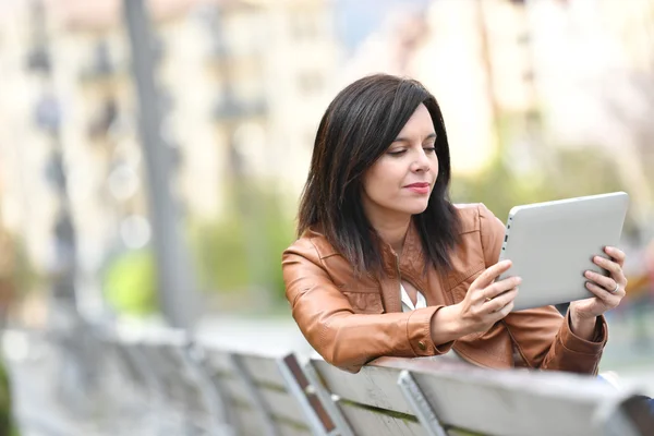 Tabletle bankta oturan kadın — Stok fotoğraf