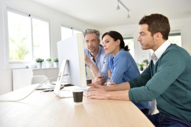  masaüstü bilgisayarda çalışan insanlar