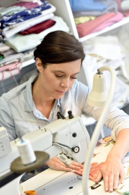 Dikiş makinesi üzerinde çalışan terzi.