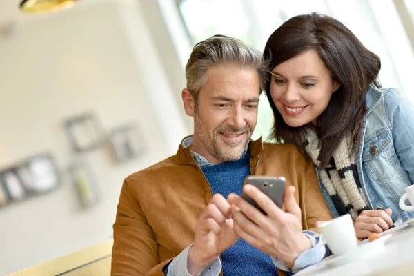 Pareja usando smartphone en cafetería —  Fotos de Stock