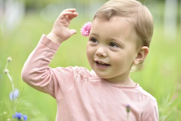 Menina jogando no campo de flores selvagens — Fotografia de Stock