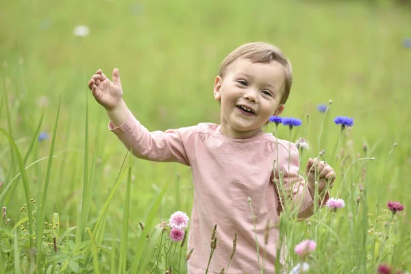 Menina jogando no campo de flores selvagens — Fotografia de Stock