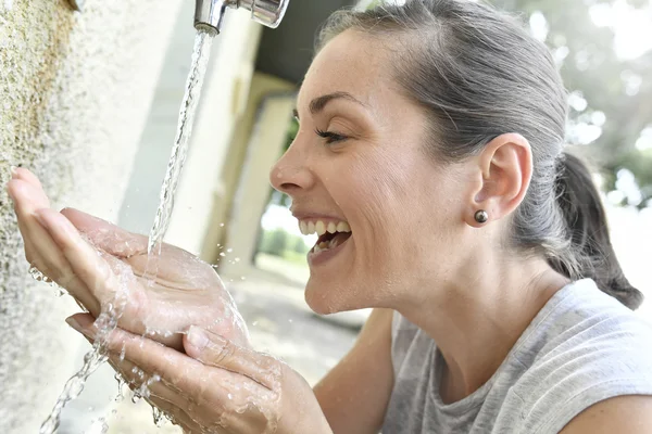 Frau trinkt Wasser aus Wasserhahn — Stockfoto