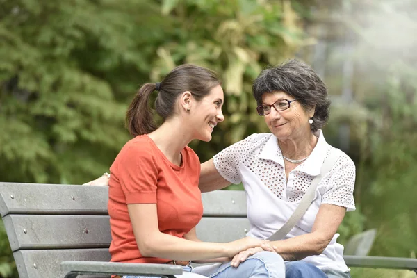 ベンチに座っている介護者を持つ女性 — ストック写真