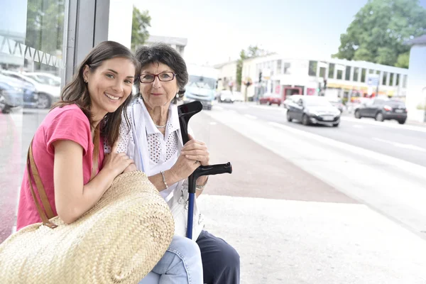 Mulher com cuidador esperando o ônibus — Fotografia de Stock