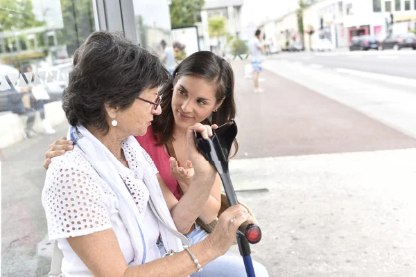 Mulher com cuidador esperando o ônibus — Fotografia de Stock