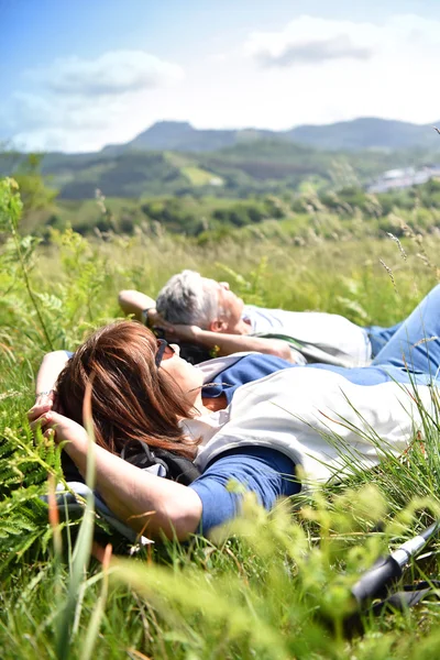 Mature couple relaxing on field — Stock Photo, Image