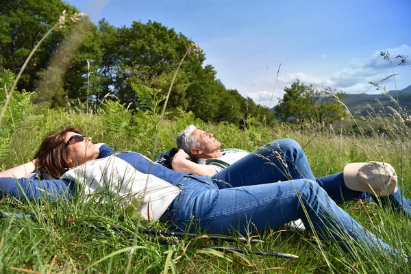 Mature couple relaxing on field — Stock Photo, Image