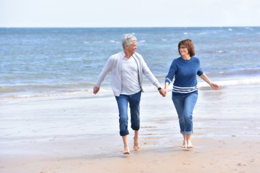  kumlu bir plaj üzerinde çalışan çift