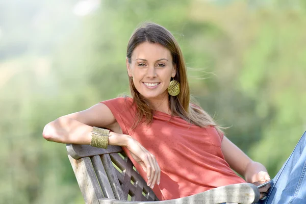 Donna in sedia da giardino in possesso di smartphone — Foto Stock