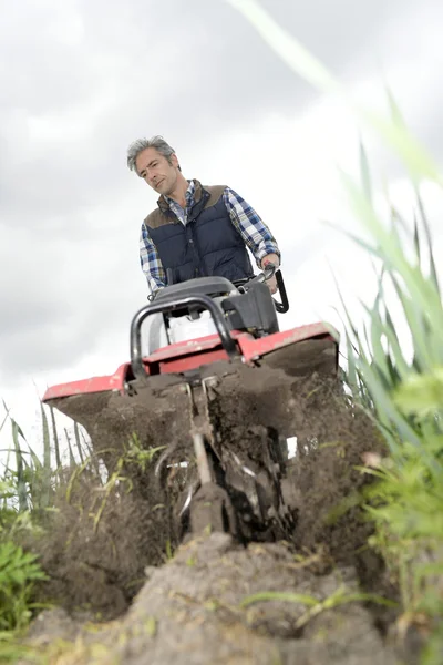 Agricultor que utiliza rototiller — Fotografia de Stock