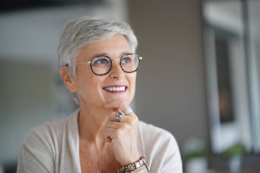 55 yaşında güzel gülümseyen beyaz saçlı bir kadının portresi.