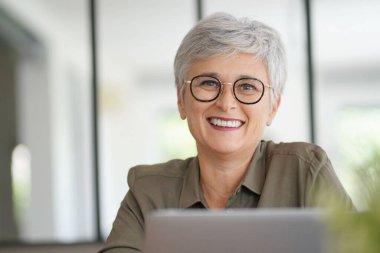 55 yaşında güzel gülümseyen beyaz saçlı bir kadının portresi.