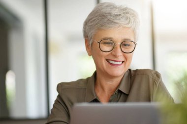 55 yaşında güzel gülümseyen beyaz saçlı bir kadının portresi.