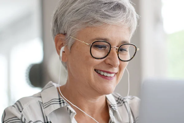 Starsza Kobieta Słuchawkami Wykonująca Wirtualne Połączenie Podczas Dystansu Społecznego — Zdjęcie stockowe