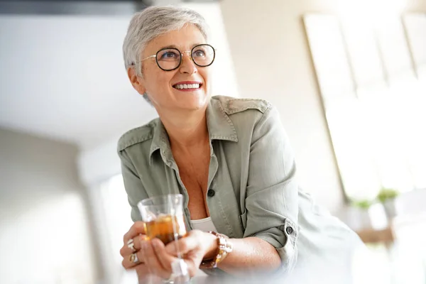 元気な50歳の女性が自宅で熱いお茶を飲んでいます — ストック写真