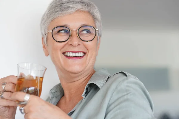 Vrolijke Jarige Vrouw Die Thuis Warme Thee Drinkt — Stockfoto