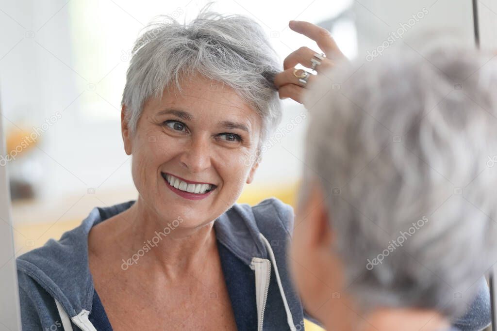 happy senior woman looking in mirror