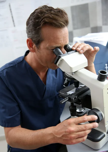 Doctor looking through microscope — Stock Photo, Image