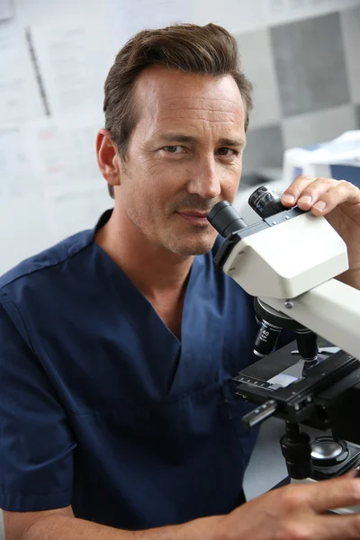 Doctor looking through microscope — Stock Photo, Image