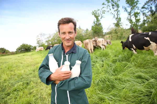 Farmer in field holding bottles of milk — Stock Photo, Image