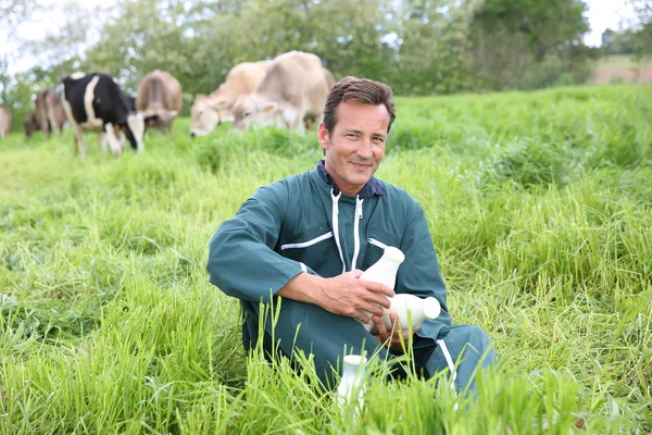 Boer in veld bedrijf flessen van melk — Stockfoto