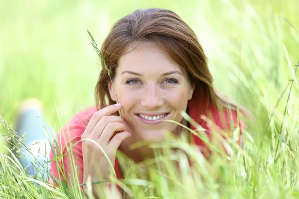 Lachende vrouw leggen in veld land — Stockfoto