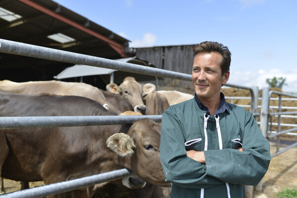 Smiling farmer standing by barn