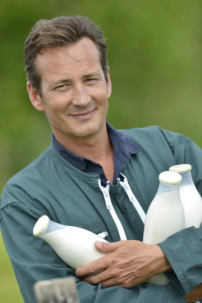 Farmer in field holding bottles of milk — Stock Photo, Image