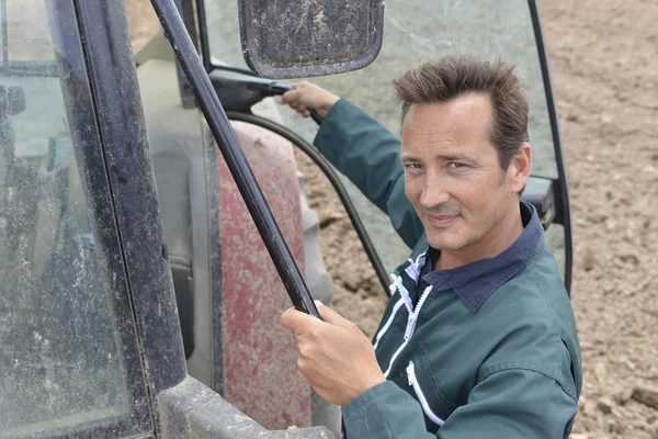 Farmer climbing into tractor — Stock Photo, Image