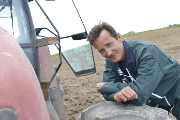 トラクターに傾いて農夫の笑みを浮かべてください。 — ストック写真